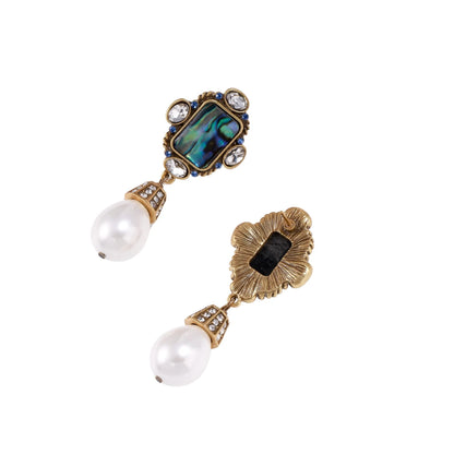 Ornate gold-plated earrings with iridescent abalone shell, crystals, blue stones, and white pearl drops on cream background.