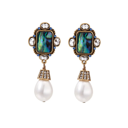 Ornate gold-plated earrings with iridescent abalone shell, crystals, blue stones, and white pearl drops on cream background.