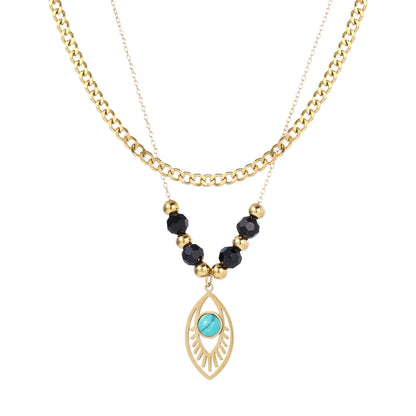 Layered gold necklace with turquoise evil eye pendant and black quartz beads on cream background