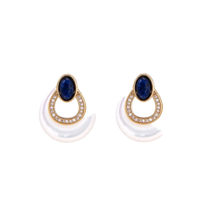 Gold drop earrings with oval lapis lazuli, crystal-paved frame, and iridescent mother-of-pearl teardrop on cream background
