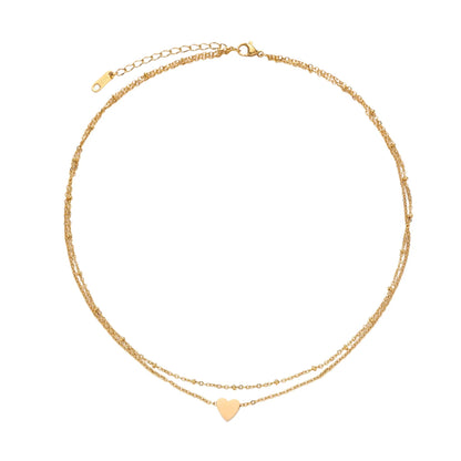 Delicate double-chain gold necklace with tiny heart pendant on cream background