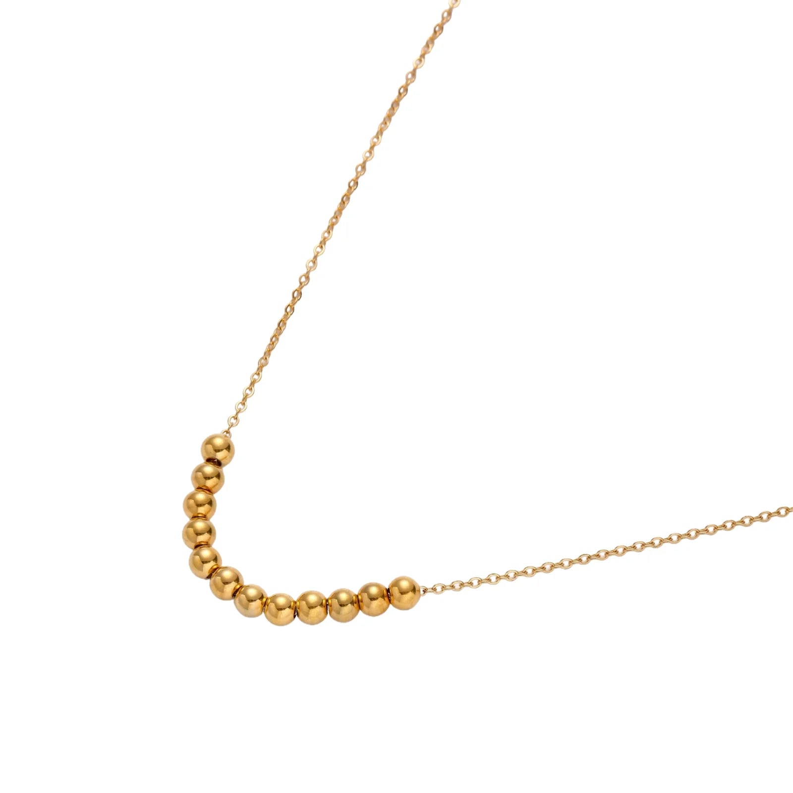 Delicate gold-plated necklace with graduated spherical beads forming gentle smile curve on beige background