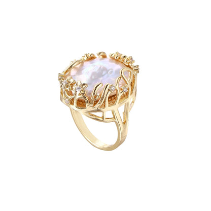 Gold filigree crown ring cradling an iridescent baroque freshwater pearl with crystal accents on white background