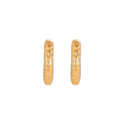 Gold-toned hoop earrings with hammered dimpled texture and post closure on cream background
