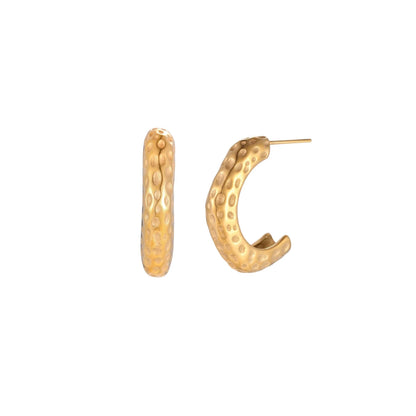 Gold-toned hoop earrings with hammered dimpled texture and post closure on cream background