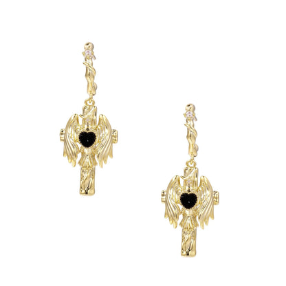 Gold angel wing drop earrings with black heart-shaped zirconia center and twisted posts on beige background