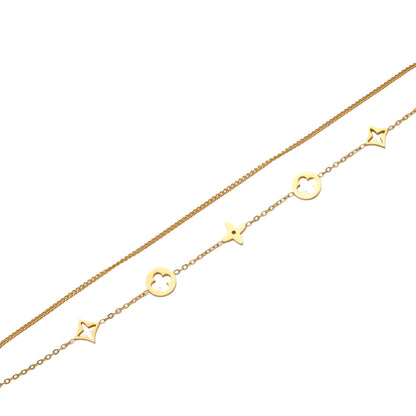 Double-layer gold-plated bracelet with quatrefoil and star charms on cream background, 18K gold finish.