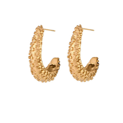 Curved gold hoop earrings with raised granulated texture resembling sea urchin surface on cream background